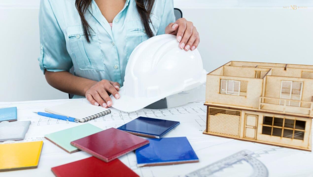 lady in her chair with a safety helmet and a model house on a table